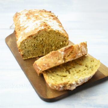 Sliced cheese and chive beer bread on a wooden board
