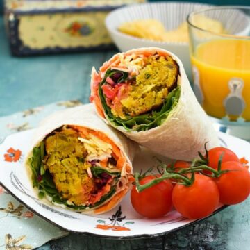 An onion bhaji wrap halved on a spotty plate